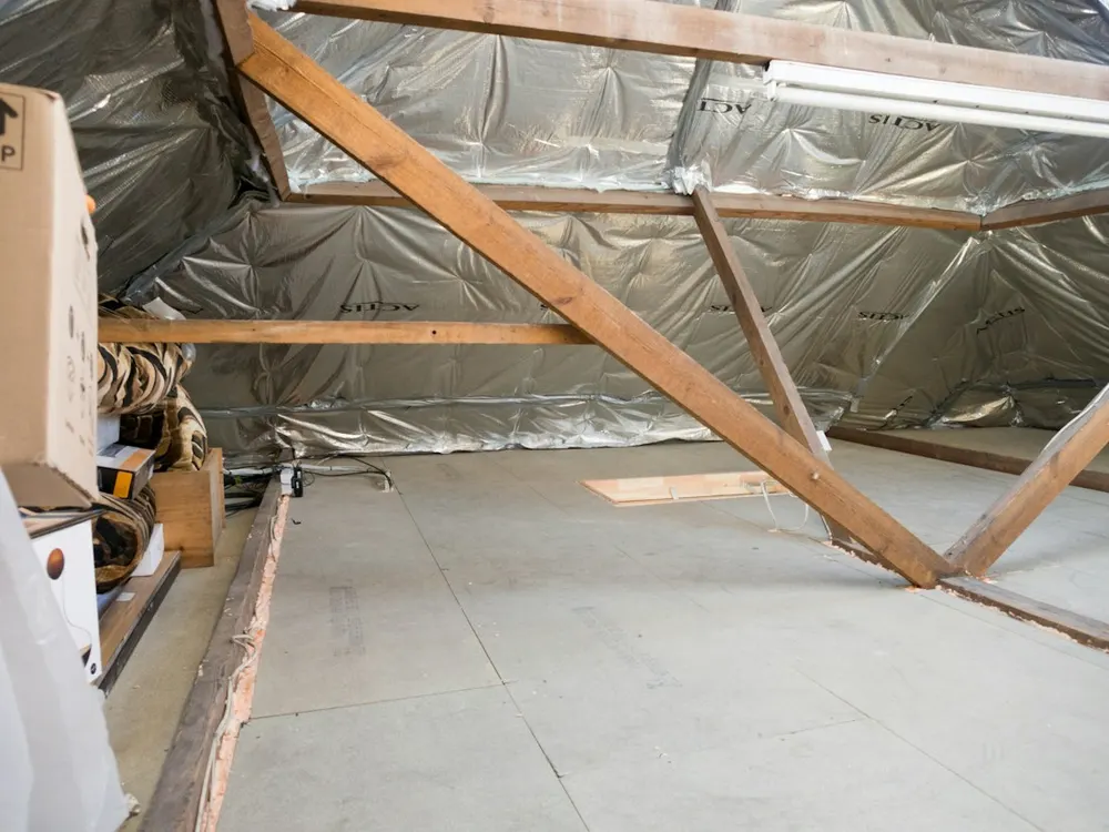 Attic interior with timber beams and insulated roof rafters