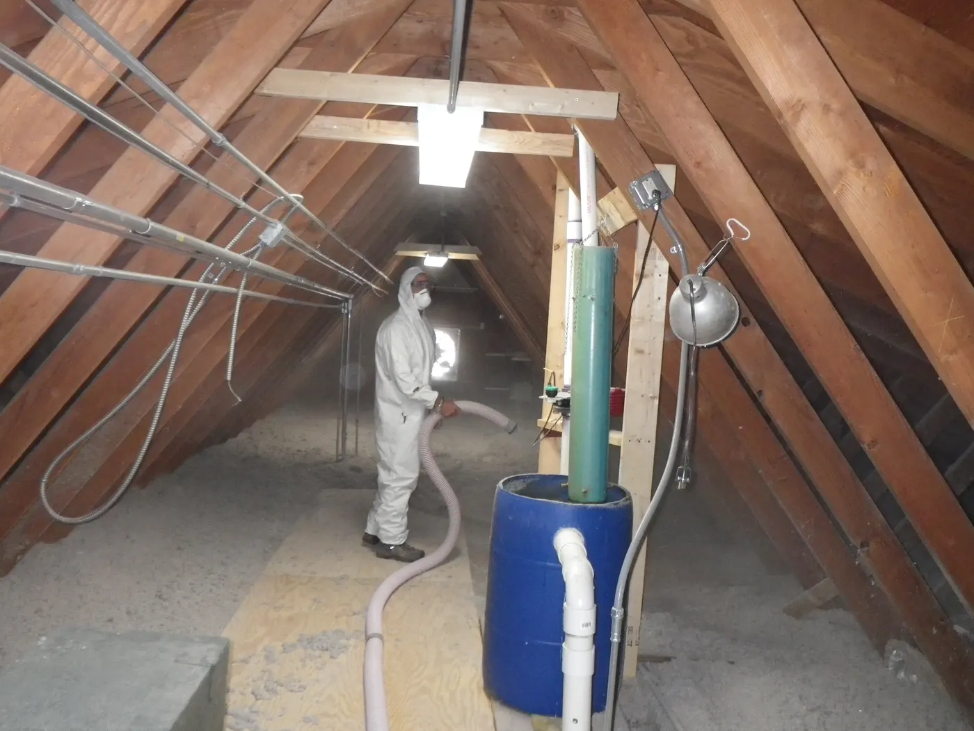 Worker blowing cellulose fibre insulation across an attic floor